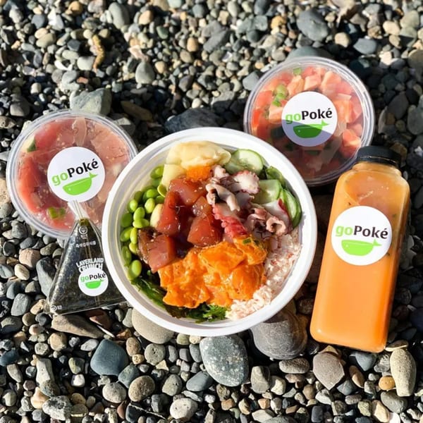 GoPoke poke bowl with tuna, salmon, octopus, edamame, and a drink on a rocky surface.